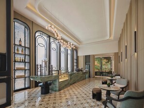 A spacious lobby with a marble floor, a reception desk, and a wine display.