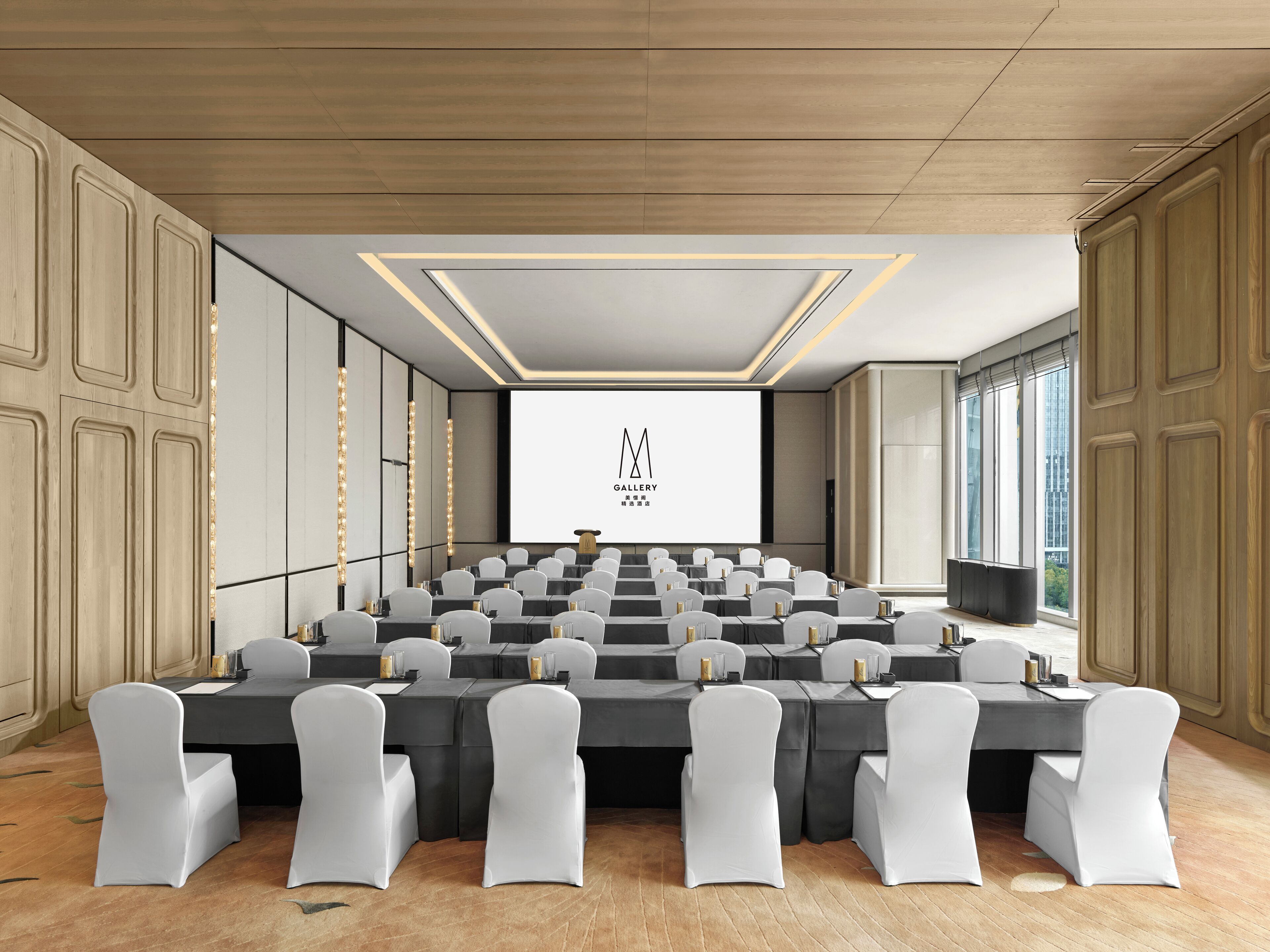 Une salle de conférence équipée d’un grand écran, de plusieurs rangées de tables et de chaises.