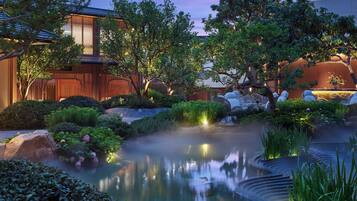 Ein friedlicher Garten mit Teich, Sitzgelegenheit und traditioneller Architektur.