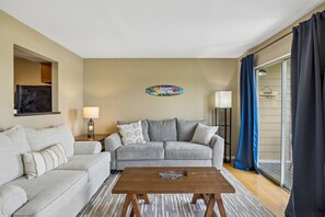 Ein Wohnzimmer mit zwei Sofas, einem Couchtisch, einer Lampe und einer Wanddekoration.