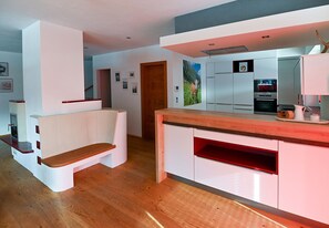 Une cuisine moderne avec des meubles blancs, un plan de travail en bois et un four encastré.