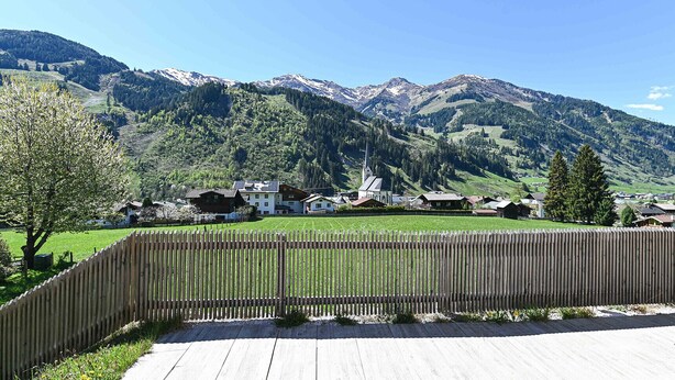 Una terraza de madera con vista a un pueblo de montaña e iglesia.