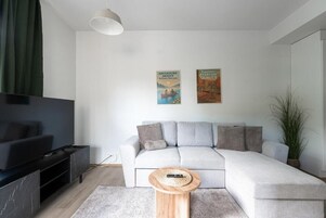 Una sala moderna con televisor de pantalla plana, sofá gris y una mesa de centro.