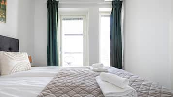 Quarto de hotel com cama, duas almofadas, uma toalha dobrada e vista para o exterior.