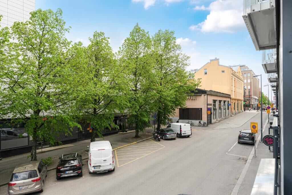 A street with parked cars, trees, and buildings.