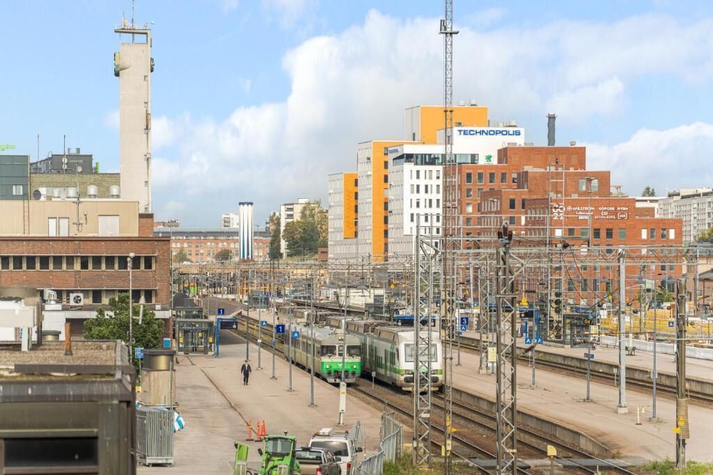 A train station with multiple tracks and a prominent building labeled 'TECHNOPOLIS'.