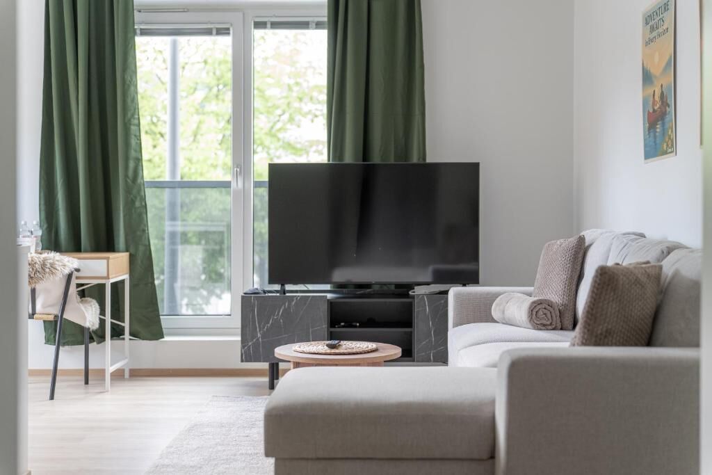 Ein modernes Wohnzimmer mit Flachbildfernseher, einer Couch, einem Couchtisch und einem Sessel.