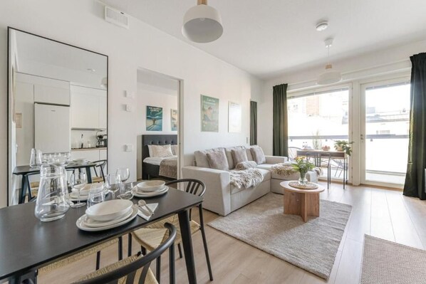 A modern living room with a dining area, a sofa, a coffee table, and a view of the outdoors.