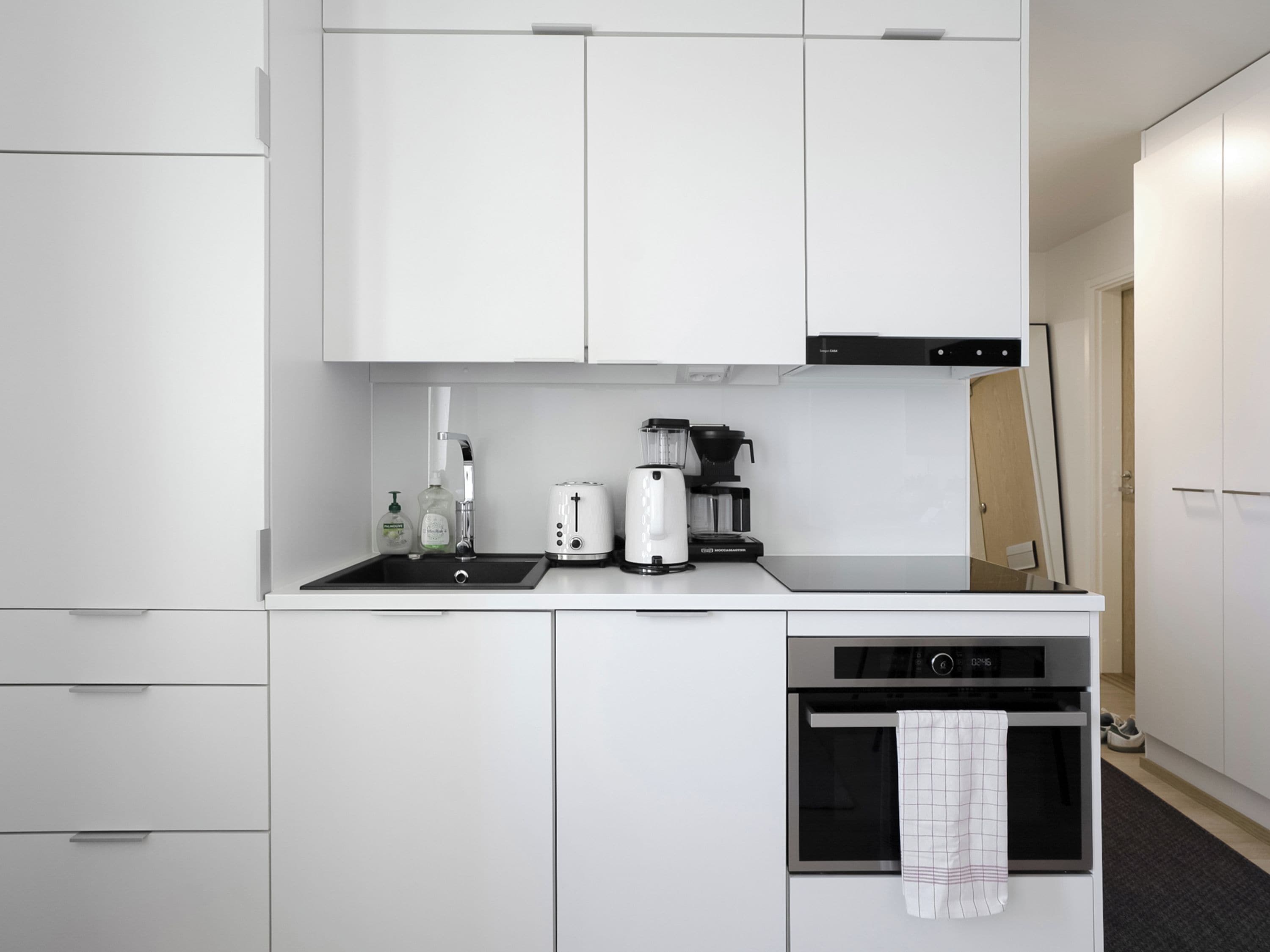 Una cocina compacta con lavamanos, tostadora, cafetera y horno.