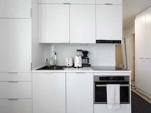 A compact kitchen with a sink, toaster, coffee maker, and oven.