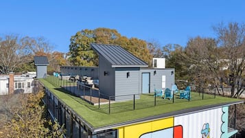A modern building with a flat roof, a green roof section, and a colorful mural on the side.