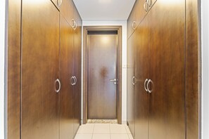 A hallway with a double door at the end, flanked by two sets of wooden wardrobes with metallic handles. - Amazing 1BR | Steps to Marina Walk, Near JBR Beach (Dubai)