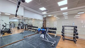 A gym with various exercise equipment, including dumbbells, a bench press, and a rowing machine. - Amazing 1BR | Steps to Marina Walk, Near JBR Beach (Dubai)
