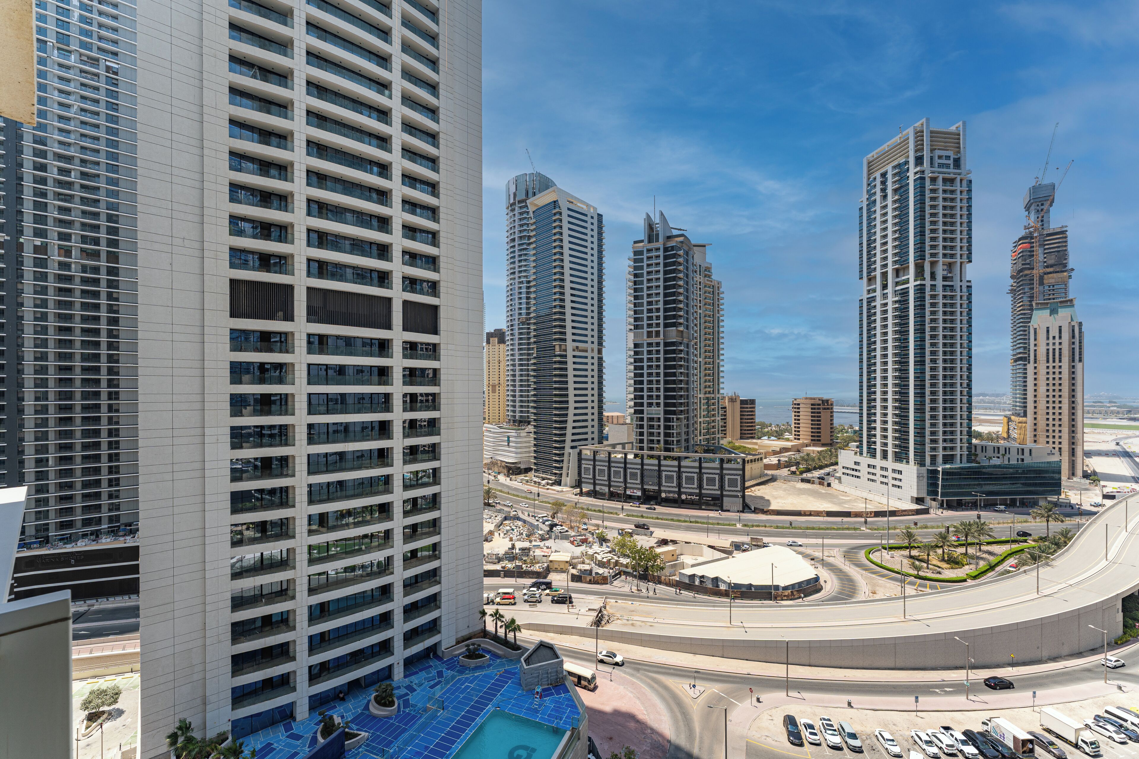 A high-rise building with a modern design, featuring a large glass facade and multiple balconies.