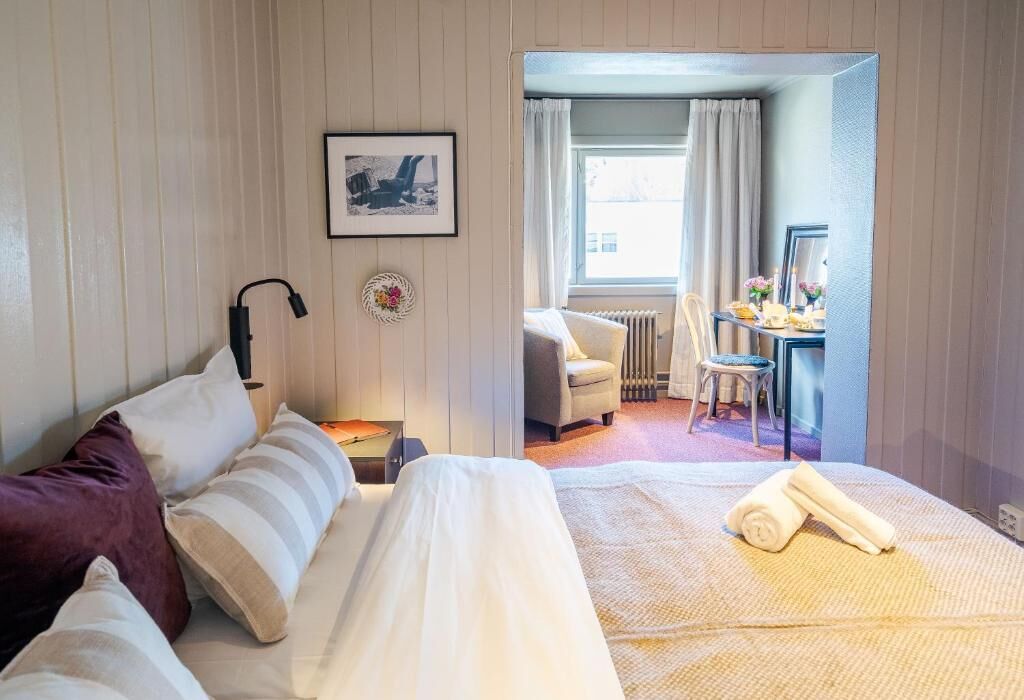 A hotel room with a bed, a desk, a chair, and a view of the outside.