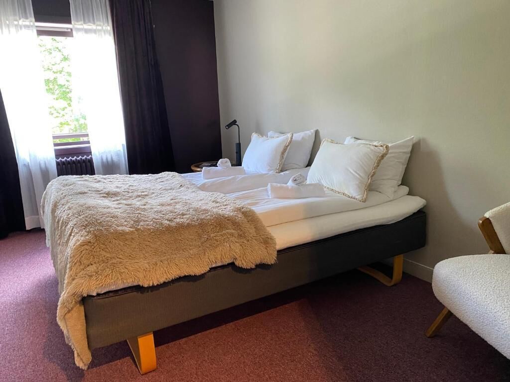 Une chambre d’hôtel avec un lit, une chaise et une vue sur la verdure.