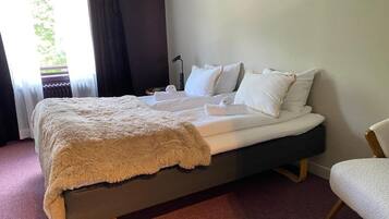 Une chambre d’hôtel avec un lit, une chaise et une vue sur la verdure.