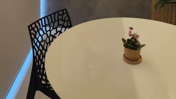 Ein Zimmer mit einem runden Tisch, einem Stuhl und einem Bild an der Wand.