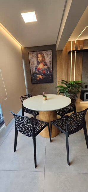 A modern dining area with a round table, black chairs, and a painting on the wall. - Comfort and sophistication next to Shopping Frei Caneca and 2 minutes from Sírio-Libanês Hospital. (São Paulo)