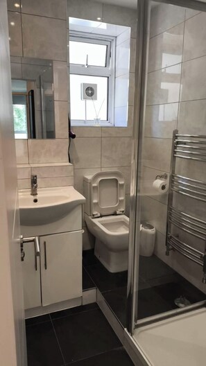 A modern bathroom with a glass shower enclosure, a toilet, a sink, and a towel rack. - Stylish two bedrooms apartment between King's Cross St Pancras and Russel Square (London)
