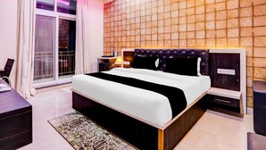 A hotel room with a large bed, a nightstand, a desk, and a view through a window.