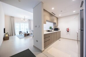 A modern kitchen with a built-in microwave, a refrigerator, and a fire extinguisher on the wall.