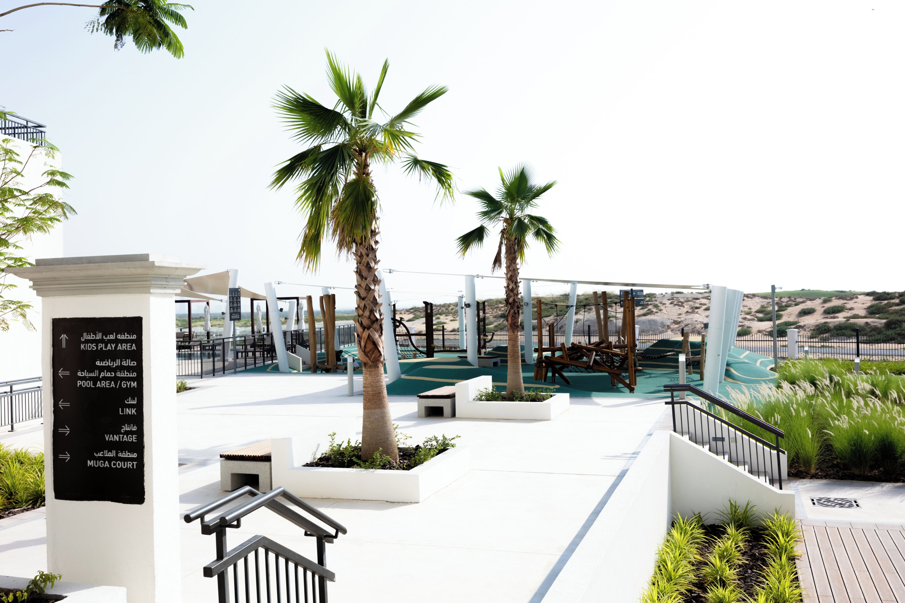 A modern outdoor area with palm trees, a play area, and a pool.
