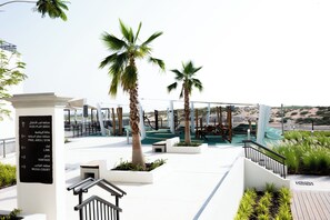 A modern outdoor area with palm trees, a play area, and a pool. - Bloomfields 1BR in Fairways 3- YGC (Abu Dhabi)