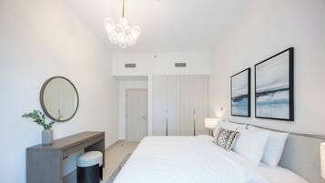 A modern bedroom with a large bed, bedside tables, a mirror, and artwork on the wall.