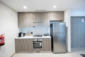 Una cocina moderna con armarios de madera, un refrigerador de acero inoxidable, horno empotrado y estufa a gas.