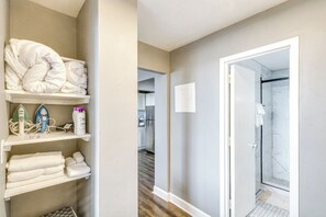 A hotel room with a shower, a hallway leading to a kitchen, and a storage area with towels and toiletries. - Downtown Atlanta High-rise Condo (Atlanta)