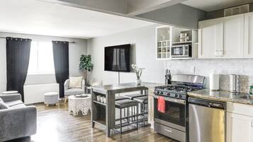 A modern kitchen with a gas stove, oven, and microwave. There is a dining area with a table and chairs.