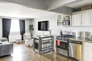Una cocina moderna con estufa a gas, horno y microondas. Cuenta con un comedor con mesa y sillas.