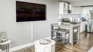 A modern kitchen with a flat-screen TV mounted on the wall, stainless steel appliances, and a bar area with stools. - Downtown Atlanta High-rise Condo (Atlanta)
