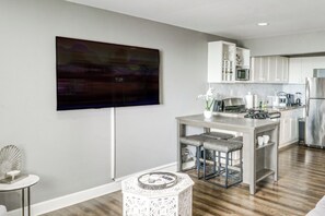 Eine moderne Küche mit Flachbildfernseher an der Wand, Edelstahlgeräten und einer Bar mit Hockern.