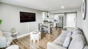 A modern living room with a grey sofa, a small round coffee table, and a flat-screen TV mounted on the wall. - Downtown Atlanta High-rise Condo (Atlanta)