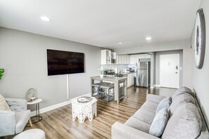 Ein modernes Wohnzimmer mit einem grauen Sofa, einem kleinen runden Couchtisch und einem flachbildfernseher, der an der Wand montiert ist.