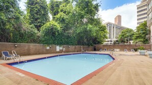 An outdoor swimming pool with a brick border, surrounded by lounge chairs and a brick wall. - Downtown Atlanta High-rise Condo (Atlanta)