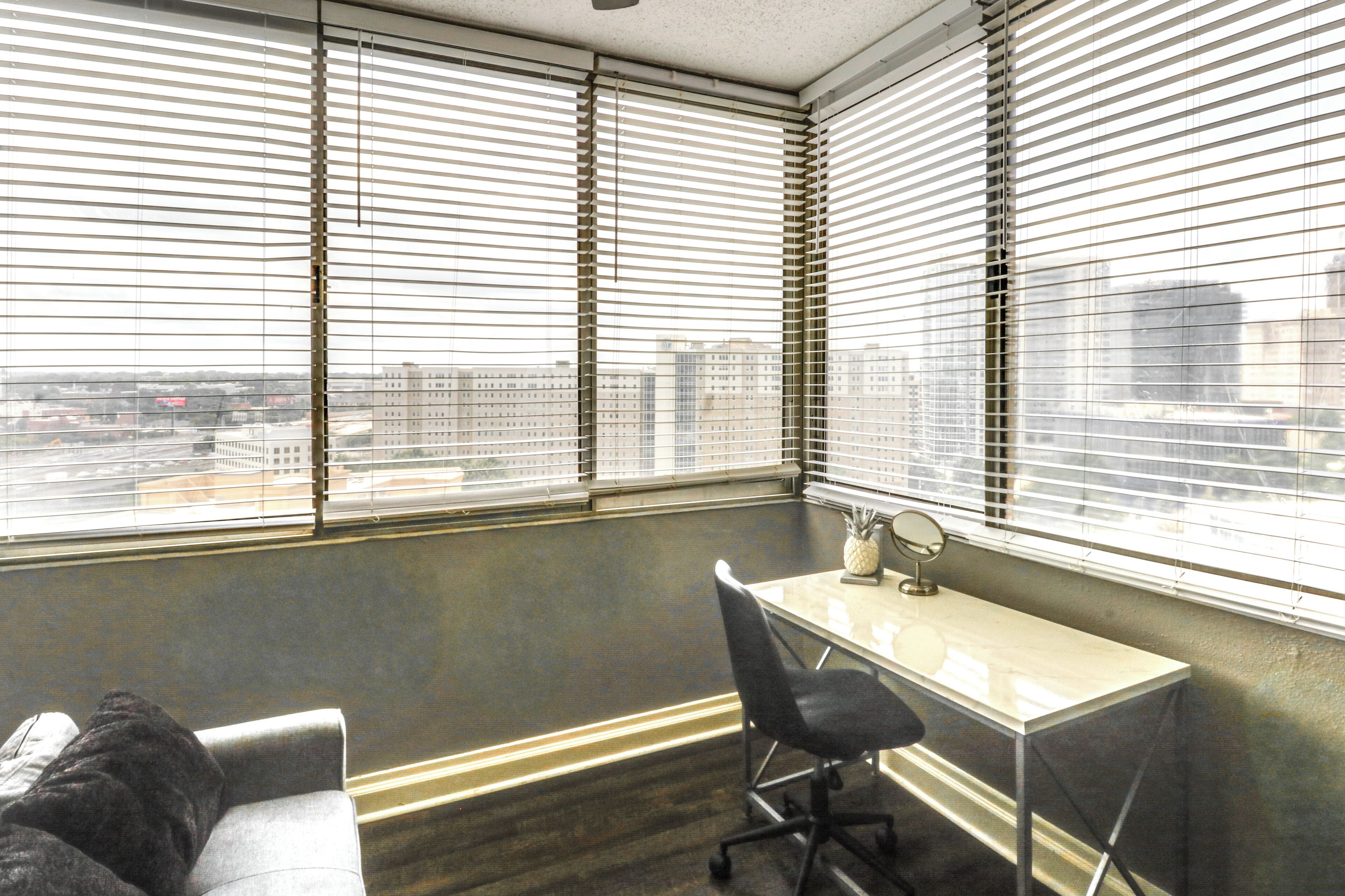 A corner office with a desk, chair, and a small table with a mirror and a pineapple.