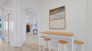 A hallway with a white bar stool set and a painting on the wall. - 4BR Golf Villa w/ Pool, Near Disney & Beaches (Davenport)
