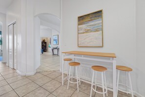 Ein Flur mit einem weißen Barhocker-Set und einem Bild an der Wand.