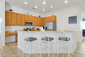Una cocina moderna con armarios de madera, electrodomésticos de acero inoxidable y una isla central con taburetes de bar.