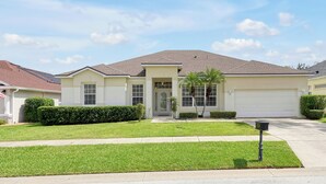 A single-story house with a front entrance, a garage, and a well-maintained lawn. - 4BR Golf Villa w/ Pool, Near Disney & Beaches (Davenport)