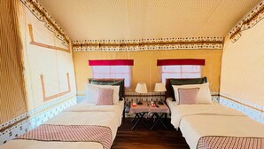 A room with two beds, a small table, and a window with a red curtain.