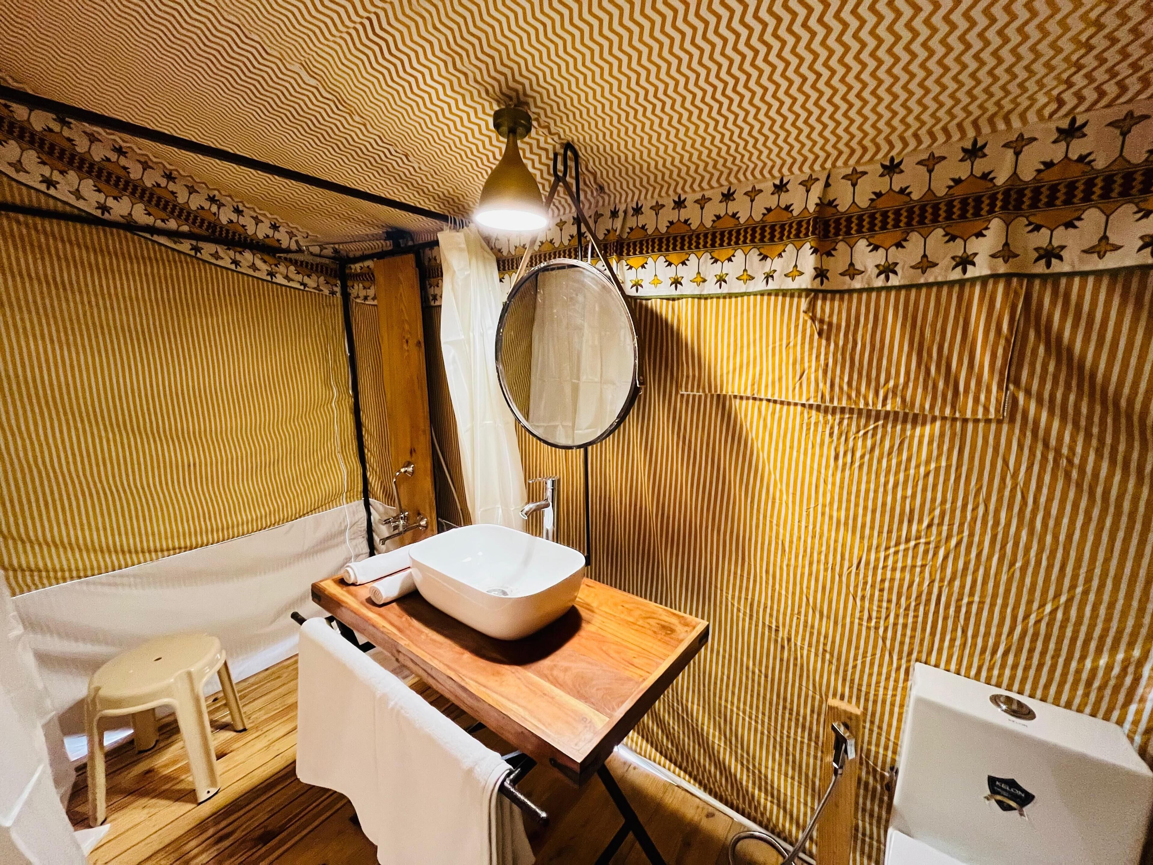 A bathroom with a wooden vanity, a white sink, a round mirror, and a bathtub.