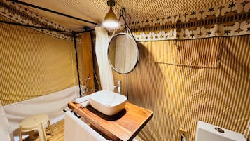 A bathroom with a wooden vanity, a white sink, a round mirror, and a bathtub.