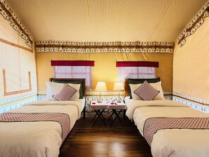 Una habitación con dos camas, una mesita con lámparas y cortinas estampadas.