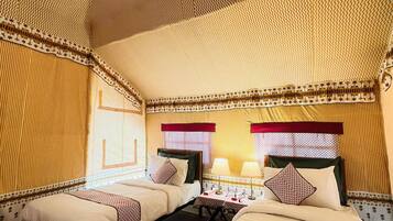 A room with two beds, a patterned ceiling, and a window with a red valance.