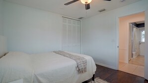 A bedroom with a bed, a ceiling fan, a closet, and a bathroom visible through an open door. - Lanai, Golf Views! Extended Sarasota Stay (Sarasota)