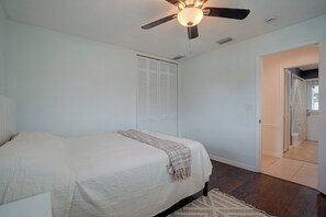 A bedroom with a bed, a ceiling fan, a closet, and a bathroom visible through an open door. - Lanai, Golf Views! Extended Sarasota Stay (Sarasota)